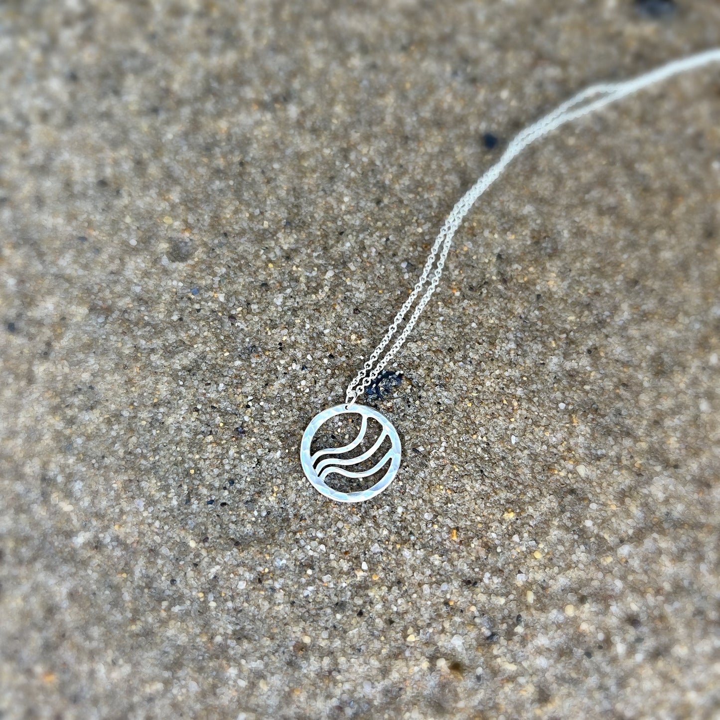 Round silver pendant with ripple waves