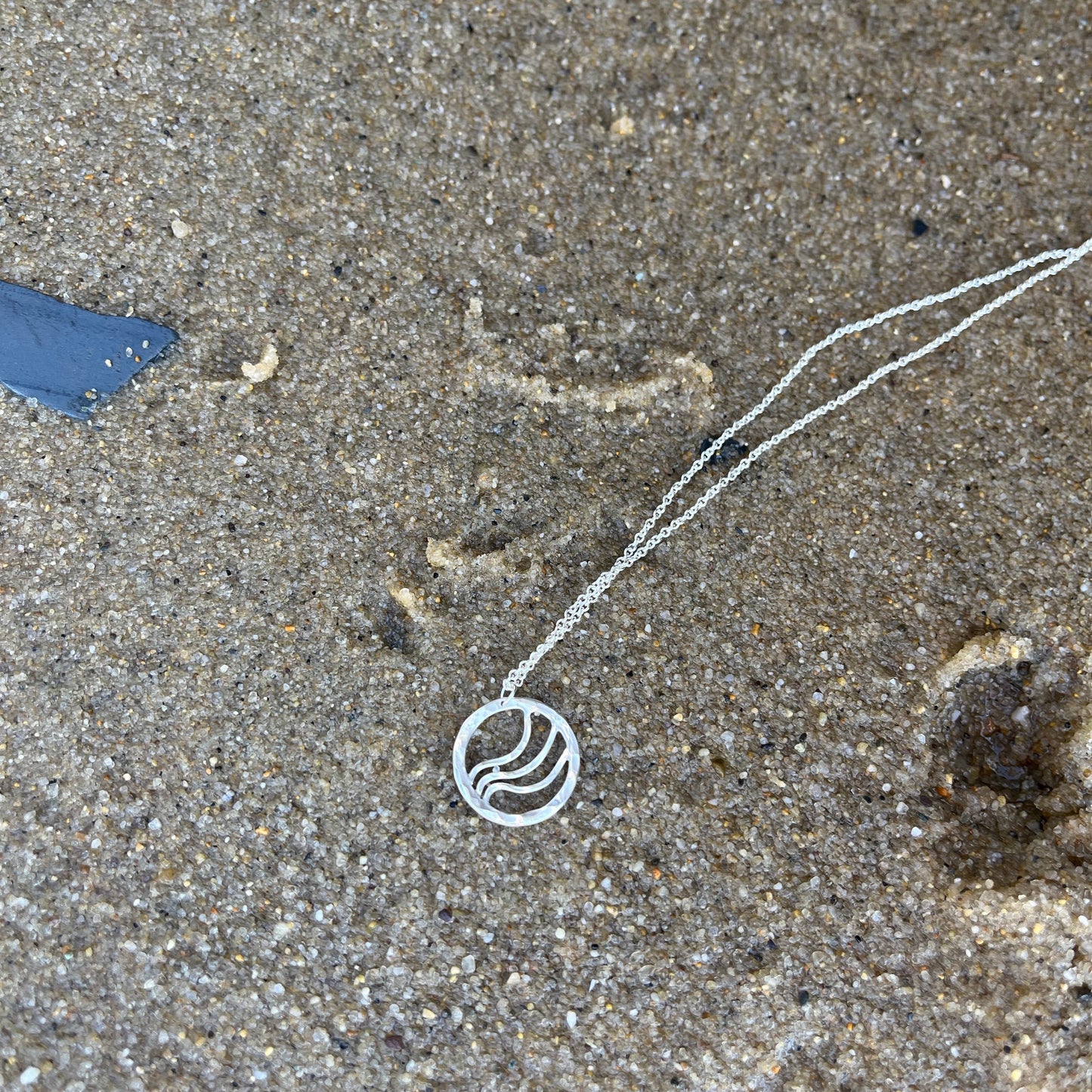 Round silver pendant with ripple waves