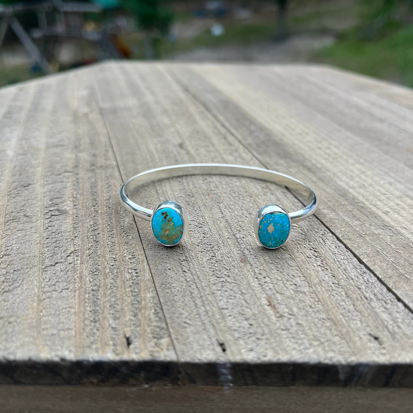 Silver bracelet with turquoise stones on a wooden surface outdoors